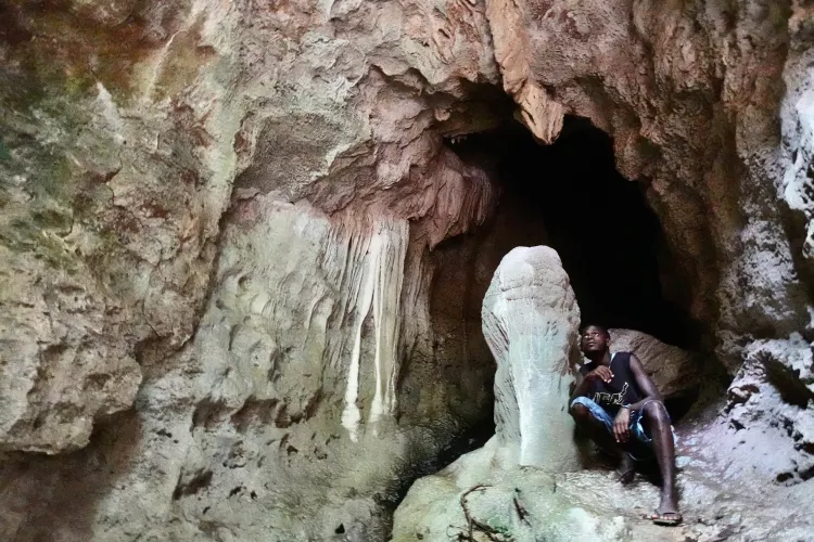 Guide Oka next to a stalagmite in a cave at Kole. Photo by Pierre Constant.